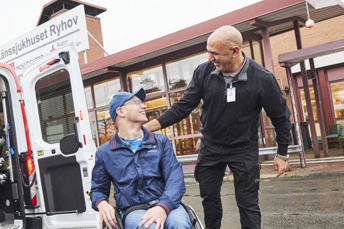 En servicereseförare och kund ler mot varandra framför Länssjukhuset Ryhov.