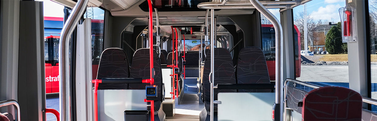 Interiören av en JLT-buss med säten i förgrunden.
