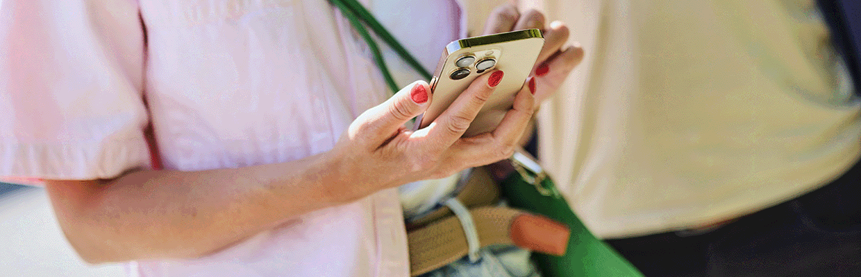 En kvinna står med sin mobiltelefon.