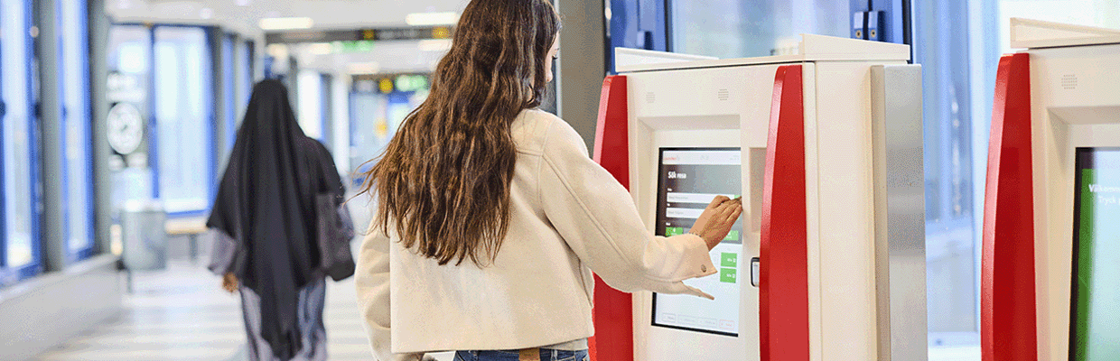 Tjej står och köper biljett i en automat.