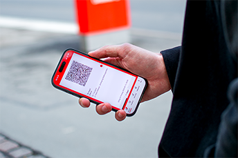 Person håller i en mobiltelefon med en QR-biljett på skärmen.