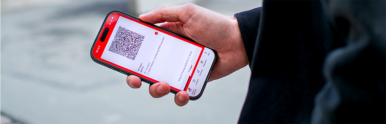 Person håller i en mobiltelefon med en QR-biljett på skärmen.