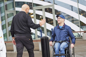 Bild på en servicereseförare som gör high five åt en kund framför Asecs entré.