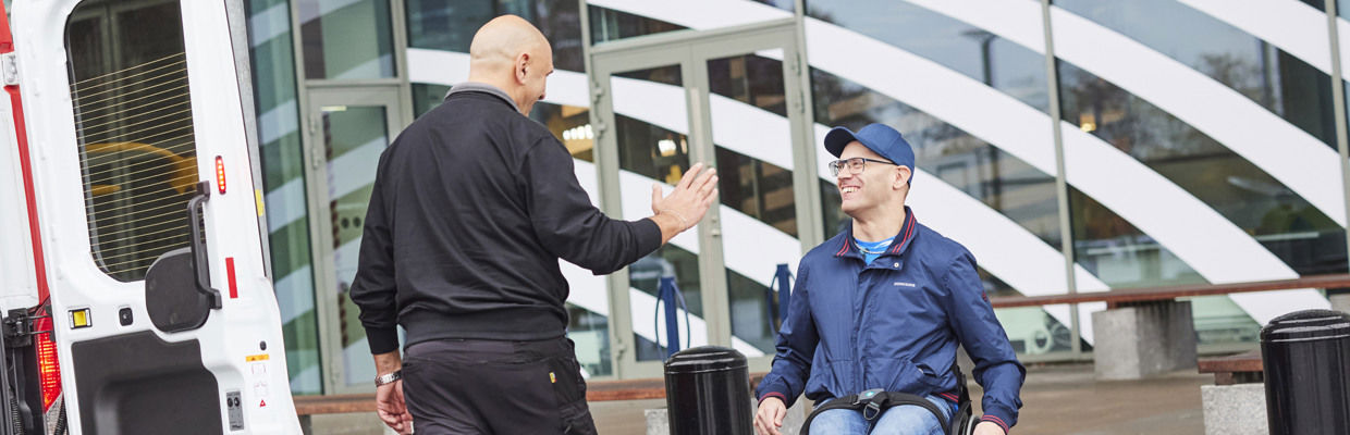 Bild på en servicereseförare som gör high five åt en kund framför Asecs entré.