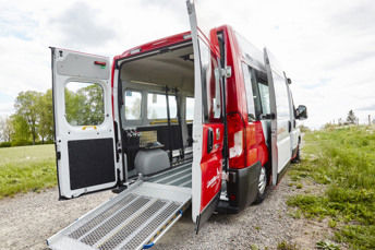 En serviceresebuss står bland sommarängar med bakdörrarna uppslagna.
