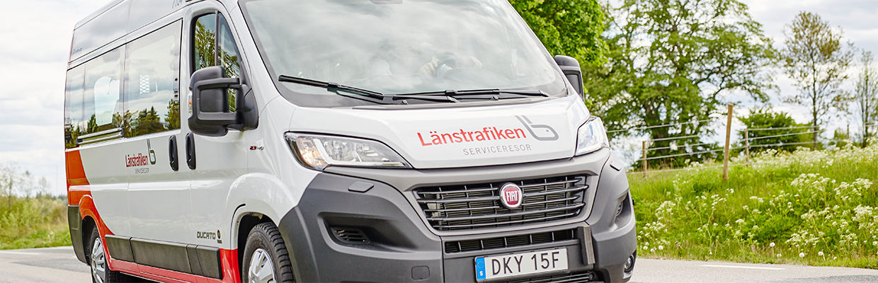 Bild på en serviceresebuss som åker bland gröna ängar.